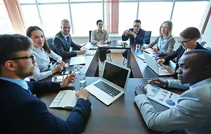 A group of co-workers sitting at a conference table having a discussion.